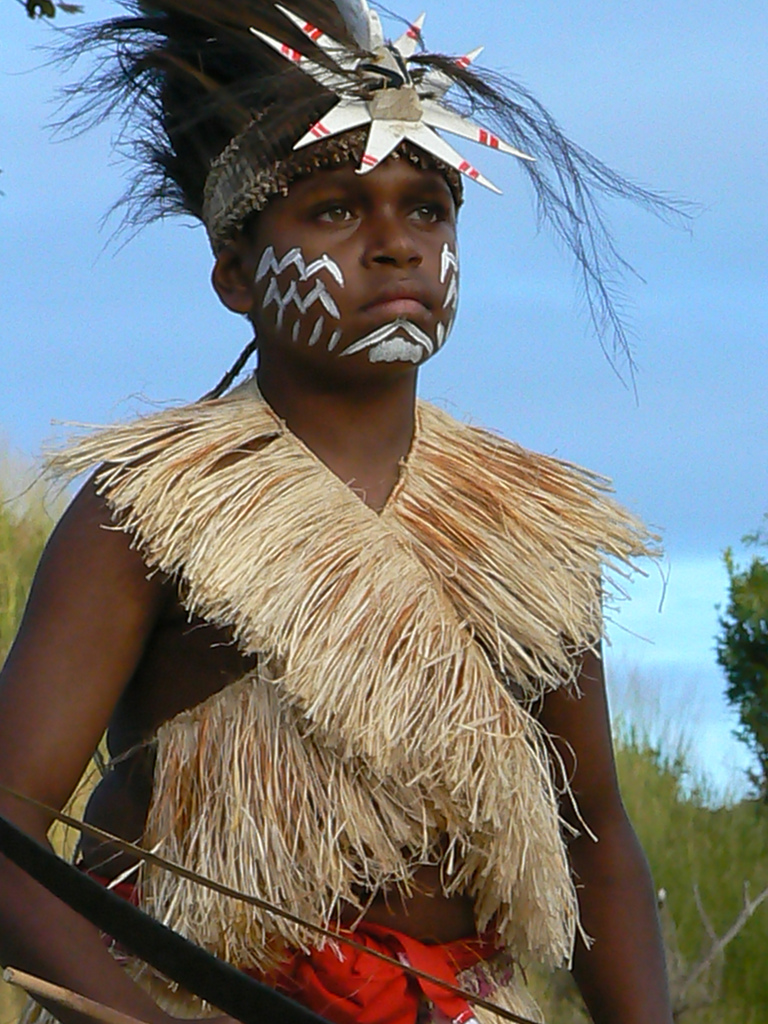 Photo of a serious-looking Torres Strait Islander boy in traditional dress.